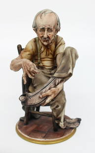 Capodimonte Tramp Darning His Socks: Capodimonte Tramp Darning His Socks. Capodimonte, made in Italy. Mid/late 20th century. To the base I.R.A Usmate. Measures 15 x 18 x 25 (height) cm. Very good condition; no chips, cracks or repairs.