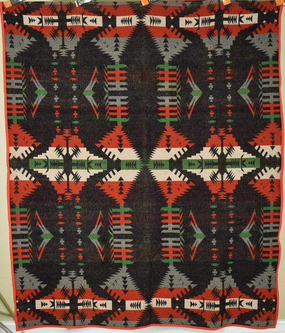 Wool Oregon City Blanket c. 1914, Indian Design: Wool "Oregon City" blanket with a black background and original label. It measures 60" X 72" and is in good condition, with overall color mellowing and no holes. An intact red felt binding surrounds t