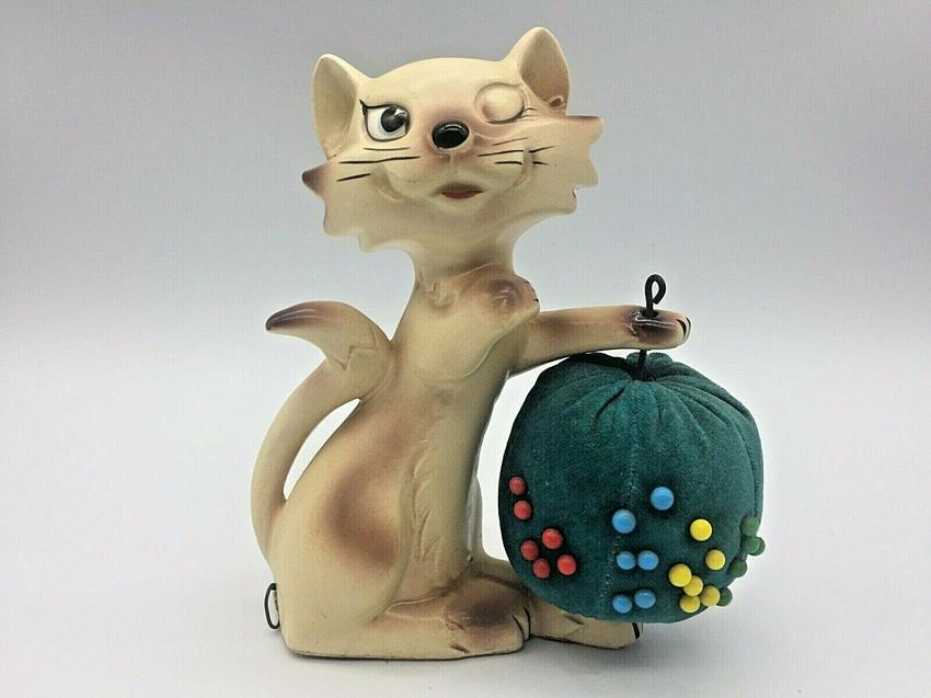SIAMESE CAT WINKING PIN CUSHION TAPE MEASURE w tag: Title: SIAMESE CAT WINKING PIN CUSHION TAPE MEASURE w tag Date/Period: Approx 1950-60's Dimension: approx 6.25" tall Materials: ceramic Additional Information: VTG JAPAN SIAMESE CAT WINKING KITTEN SEW