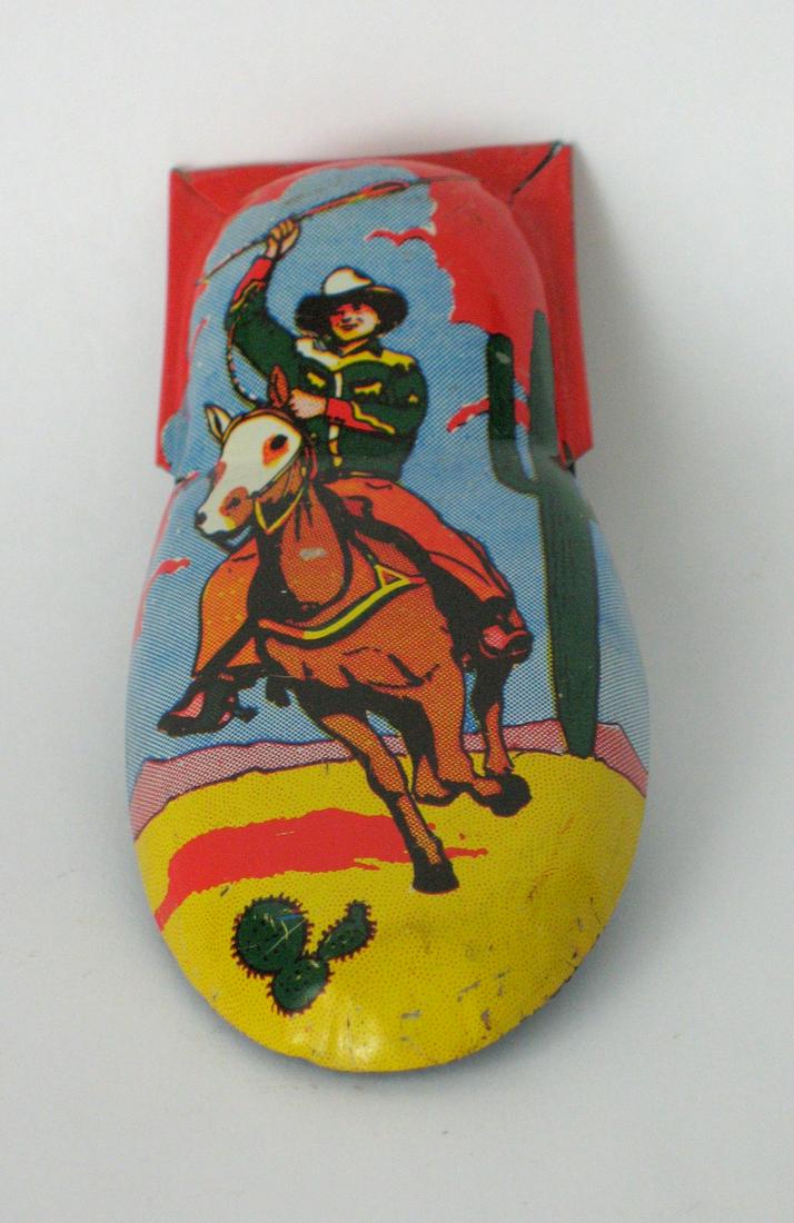 Vintage tin cowboy design toy clicker.: Title: Vintage tin cowboy design toy clicker. Dimension: 4 1/4” x 2” Date/Period: 1950's Additional Info:Nice vintage toy clicker or noise maker with a cowboy design in great original cond