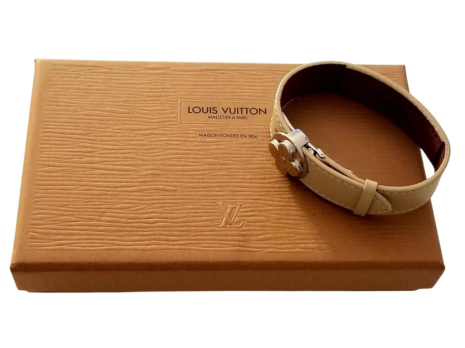 Louis Vuitton Wish Good Luck Beige Patent Leather Bracelet: Louis Vuitton Wish Good Luck Beige Patent Leather Bracelet. We offer this Wish Good Luck Fleur Bracelet in a beige patent leather. The strap features an adjustable clasp and silver-tone hardware. The 