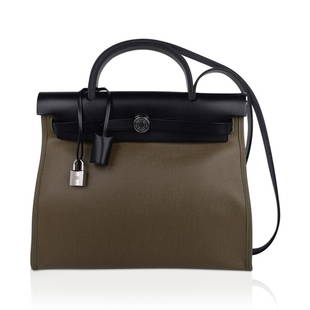 Hermes Herbag Zip Retourne 31 Khaki Berline/ Black Leather Palladium: Hermes Herbag Zip 31 featured in Khaki Berline canvas and Black leather. Signature Herbag Clou de Selle in Palladium hardware. Bag has Toile removable pochette. Comes with lock, keys and clochette,