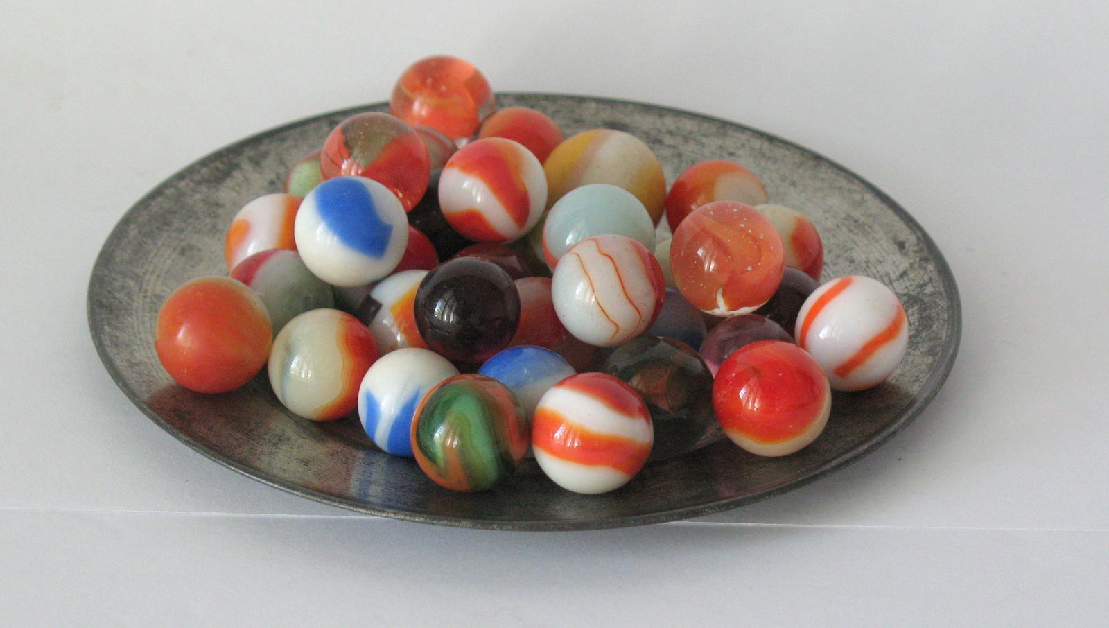 Group Of Vintage Glass Marbles: Title: Group of vintage glass marbles. Provenance/Additional Info: Nice collection of 59 vintage glass marbles in great condition. Does not include the small pewter plate! Dimensions: normal size Circ