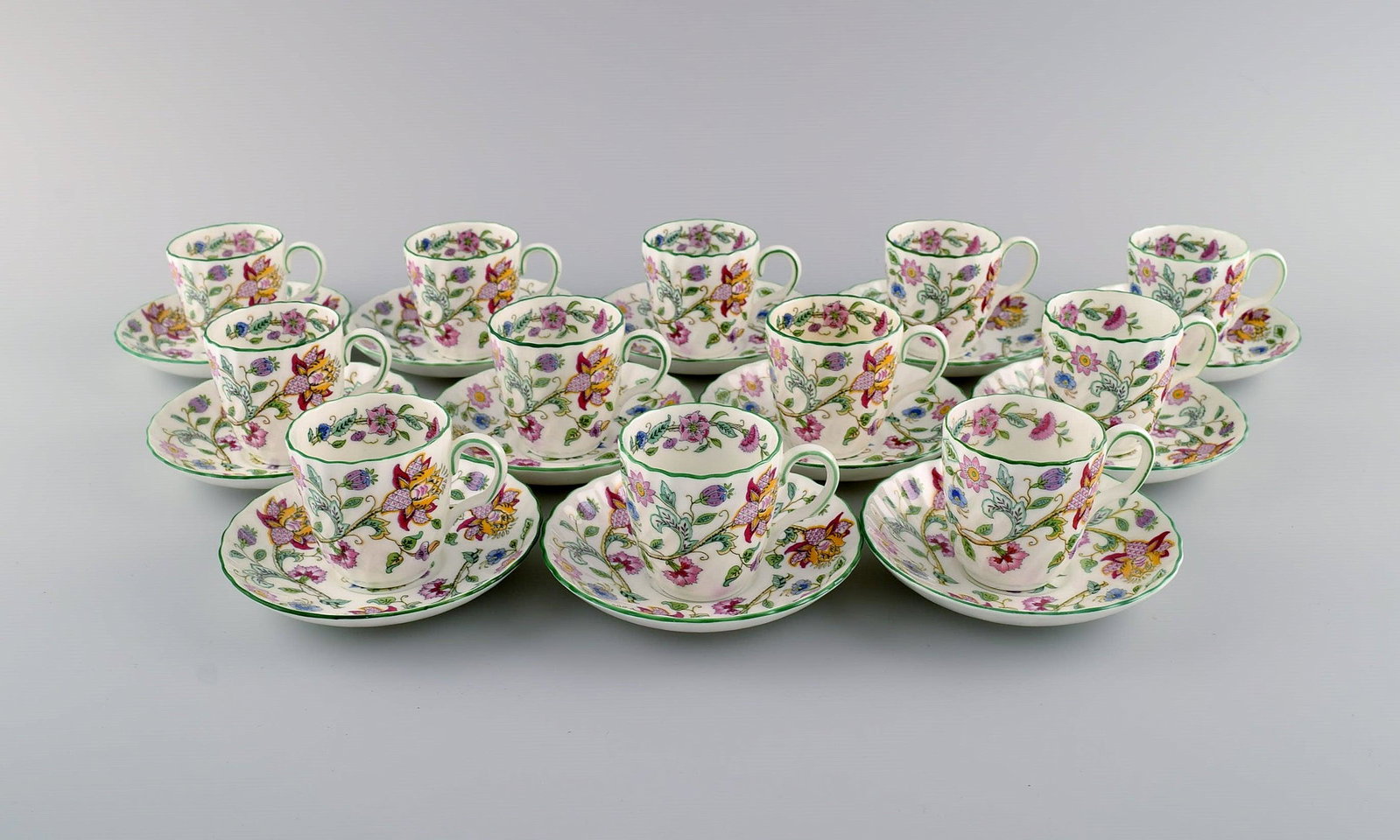 Minton, England. Twelve Haddon Hall mocha cups with porcelain saucers. Colorful flowers and light: Minton, England. Twelve Haddon Hall mocha cups with porcelain saucers. Colorful flowers and light green border. 1930s. The cup measures: 5.7 x 5.5 cm. Saucer diameter: 11 cm. In excellent condition. S