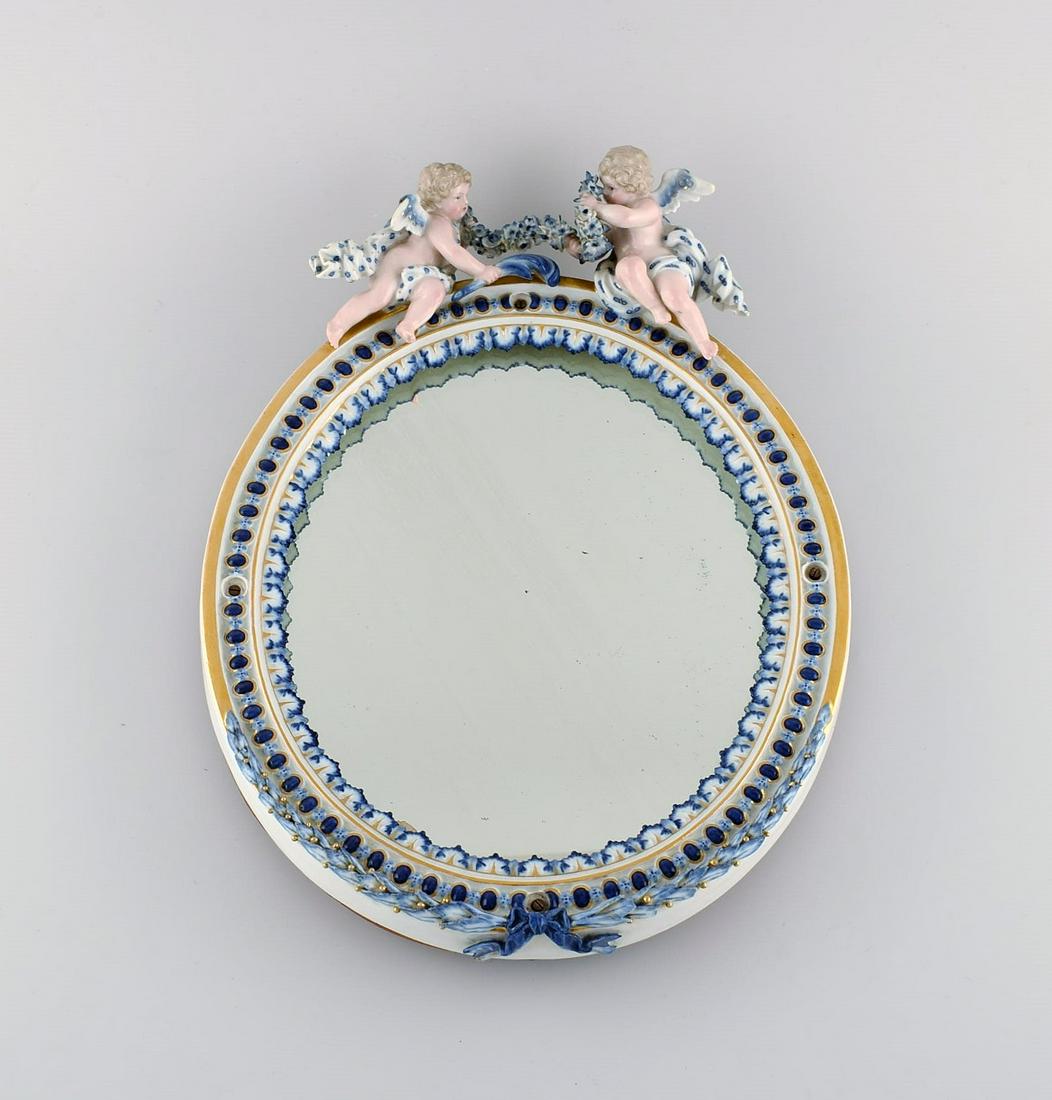 Antique Meissen porcelain mirror with original glass. Decorated with angels and repousse flowers.: Antique Meissen porcelain mirror with original glass. Decorated with angels and repousse flowers. Late 19th century. Measures: 34.5 x 25.5 cm. In very good condition. One wing cut. Stamped. 1st factor