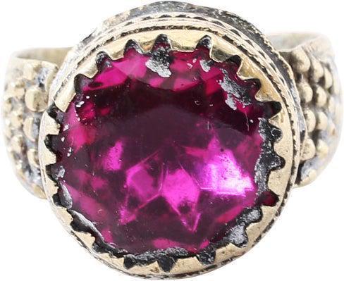 EASTERN EUROPEAN GYPSY RING, SIZE 9 1/4: 19th century, white metal with 4.6mm band flaring to the shoulders which are decorated with foliage and grapes (?). Tall banded cylindrical bezel set with a large faceted red "stone". Charming garish 
