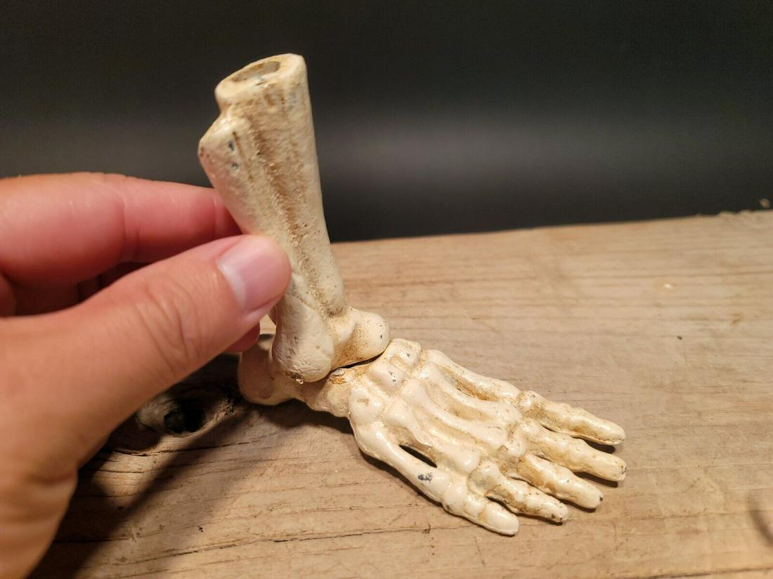 Cast Iron Halloween Skeleton Foot Pen Holder: 4 1/2" Long x 1 3/4" Wide 4" tall Great reproduction cast iron foot pen holder. This piece was made to look just like an antique but is new. As you see in the images it is in the form of a skeletal fo