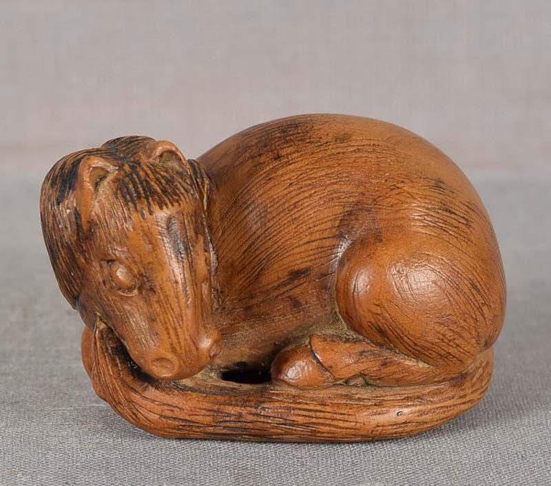 19c netsuke RESTING HORSE: 19th century boxwood netsuke of a resting horse with head turned to the left, its legs bent beneath its body. Beautifully carved, wonderful face with great depiction of its body bulk and flow of its m