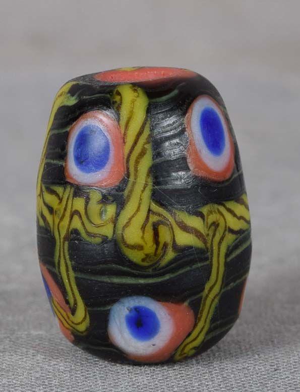 19c glass OJIME netsuke slide: 19th century glass ojime (slide bead for tightening the cord going from netsuke to inro) in barrel shape with red body with black overlay, red, white and blue concentric circled and yellow rope design