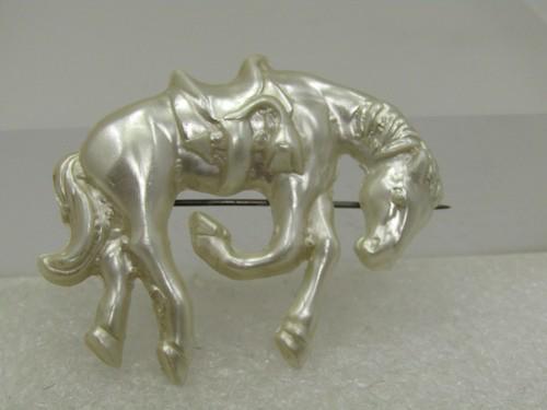 Vintage Celluloid Horse/Bucking Bronco Brooch, 1940's: Vintage Celluloid Horse/Bucking Bronco Brooch, 1940's. Pearly white with a saddle and horse in a bucking pose. It is appx. 2" by 1.75. Plastic c-clasp. Very good condition. Great for rodeo and equine
