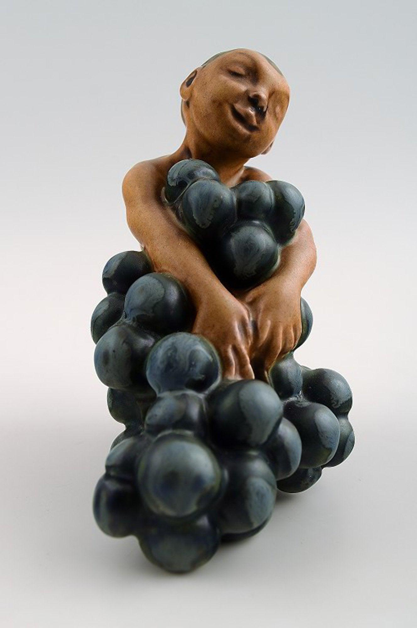 Bing & Grondahl stoneware figurine of small bacchus with bunch of grapes by Kai Nielsen. Model: Bing & Grondahl stoneware figurine of small bacchus with bunch of grapes by Kai Nielsen. Model number 4027. From the series 'Grape Harvesting'. Measures 11 cm. x 11 cm. 1. Quality, in perfect conditio