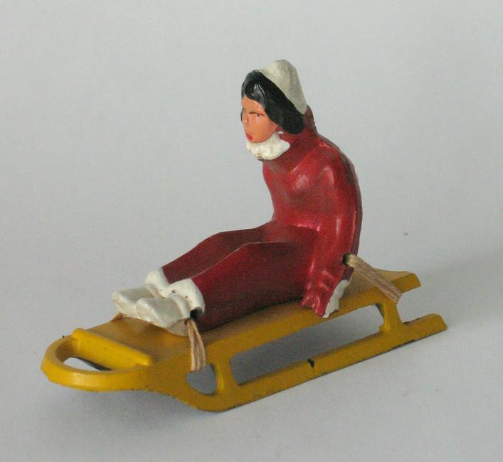 Vintage Cast Metal Sled & Rider: Title: Vintage cast metal sled & rider. Circa: 1930's Dimension: 3" long Additional Information: Nice vintage cast metal yellow sled and a rider dressed in red, made in England (two pieces). Shipping:
