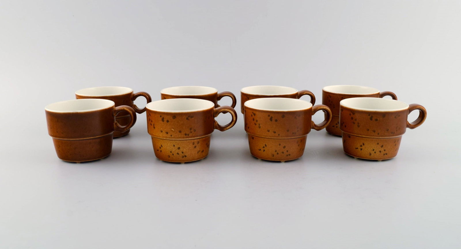 Stig Lindberg for Gustavsberg. Eight Coq coffee cups in glazed stoneware. Beautiful glaze in brown: Stig Lindberg for Gustavsberg. Eight Coq coffee cups in glazed stoneware. Beautiful glaze in brown shades. Swedish design, 1960s. Measures: 7.5 x 6 cm. In excellent condition. Stamped. Reserve: $280.0
