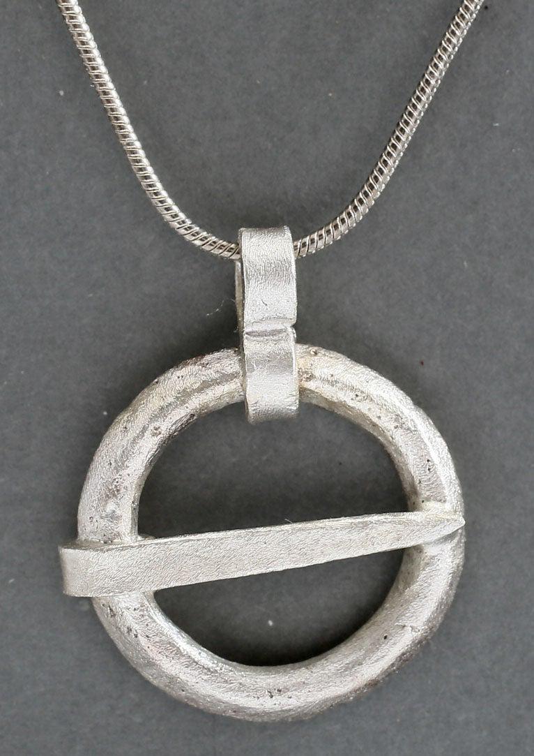 VIKING PROTECTIVE BROOCH, C.900-1050 AD: Silvered bronze of broad form, just under 7/8" diameter. Broad rounded face front and back meeting as a ridged edge. When fastened to the jerkin, these small metal brooches provided a measure of prote