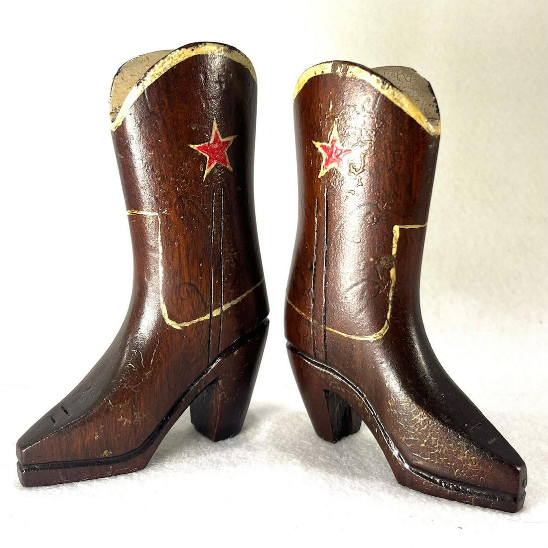 MID-20TH CENTURY HAND CARVED COWBOY BOOTS: Mid-20th century hand carved wooden cowboy boots with painted highlights. Approximate height is 5-1/2” and length from tip to heel is 3-1/4”. Condition: original surface. Surface soiling, 