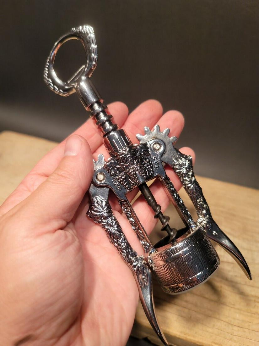 Ghidini Italy Wine Bottle Corkscrew Opener: 8" Tall x 3" Wide Such a neat vintage style Ghidini corkscrew made in Italy. As you can see the corkscrew is covered in grape and wine barrel designs. Nice heavy metal design. New in the box never use