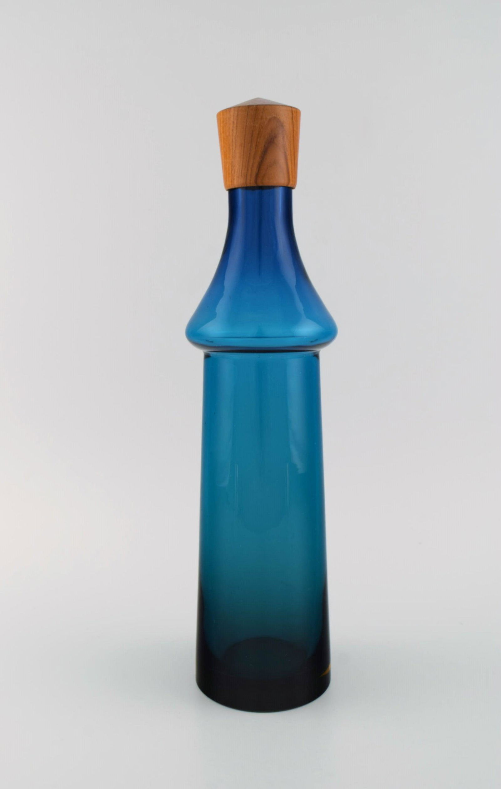 Göran Wärff for Pukeberg. Large Tropico decanter in blue mouth-blown art glass with teak stopper.: Goran Wärff for Pukeberg. Large Tropico decanter in blue mouth-blown art glass with teak stopper. Swedish design, 1960s. Measures: 37 x 10 cm. In excellent condition. Reserve: $350.00 Shipping: D