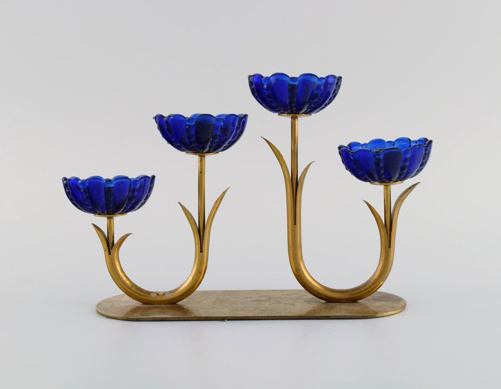 Gunnar Ander for Ystad Metall. Candlestick in brass and blue art glass shaped like flowers. 1950s.: Gunnar Ander for Ystad Metall. Candlestick in brass and blue art glass shaped like flowers. 1950s. Measures: 21 x 12.5 x 6.5 cm. In excellent condition with patina. Can be polished so that it appears