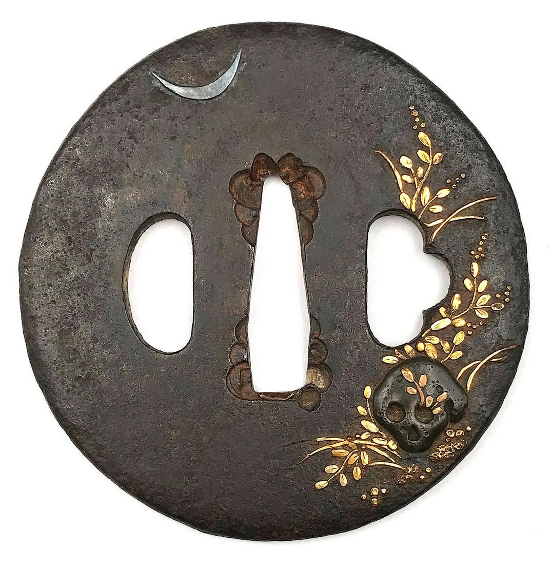 Iron tsuba with skull and grasses under crescent moon motif: Title: Iron tsuba with skull and grasses under crescent moon motif Date/Period: Edo period Dimension: 71.7 x 70.6 x 4.2 mm Materials: Iron, gold, shakudō Additional Information: TSU-0175. An iron