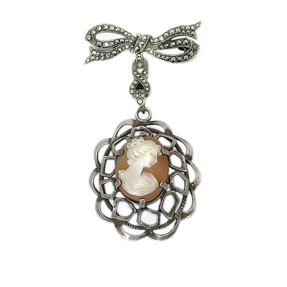 Cameo Pendant on Watch Pin: A maked 800 silver and marcasite ribbon shaped watch pin hooked with a carved portrait cameo pendant with silver frame. They are from the 1930s. Dimensions: 1.25 x 0.25 x 1.5 inch pin; 1.38 x 1.63 x 0