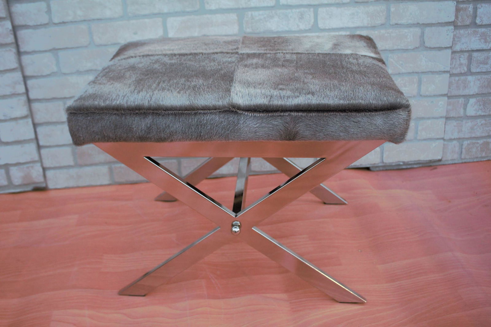 Modern Tangent Chrome X Design Stool with Cow Hide Top: Read the full list of materials Materials: chrome, cow hide, animal skin, metal Description Modern Tangent Chrome Flat Bar X Design Base Stool with Gray Cow Hide Top Circa 2019 H 18” W 23”