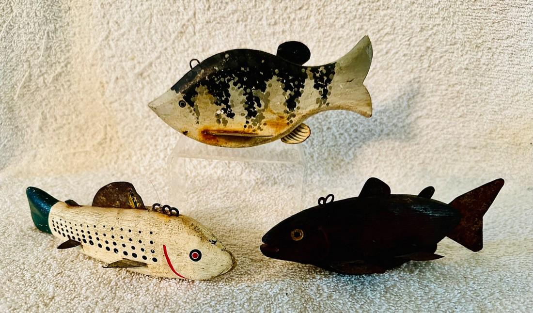 3 Carved Wood Fishing Lures: 3 mid-20th Century carved wooden fishing lures that were probably used for ice fishing. Each has tin fins and places to attach a fishing line. The dark brown lure on the right of the picture also has 
