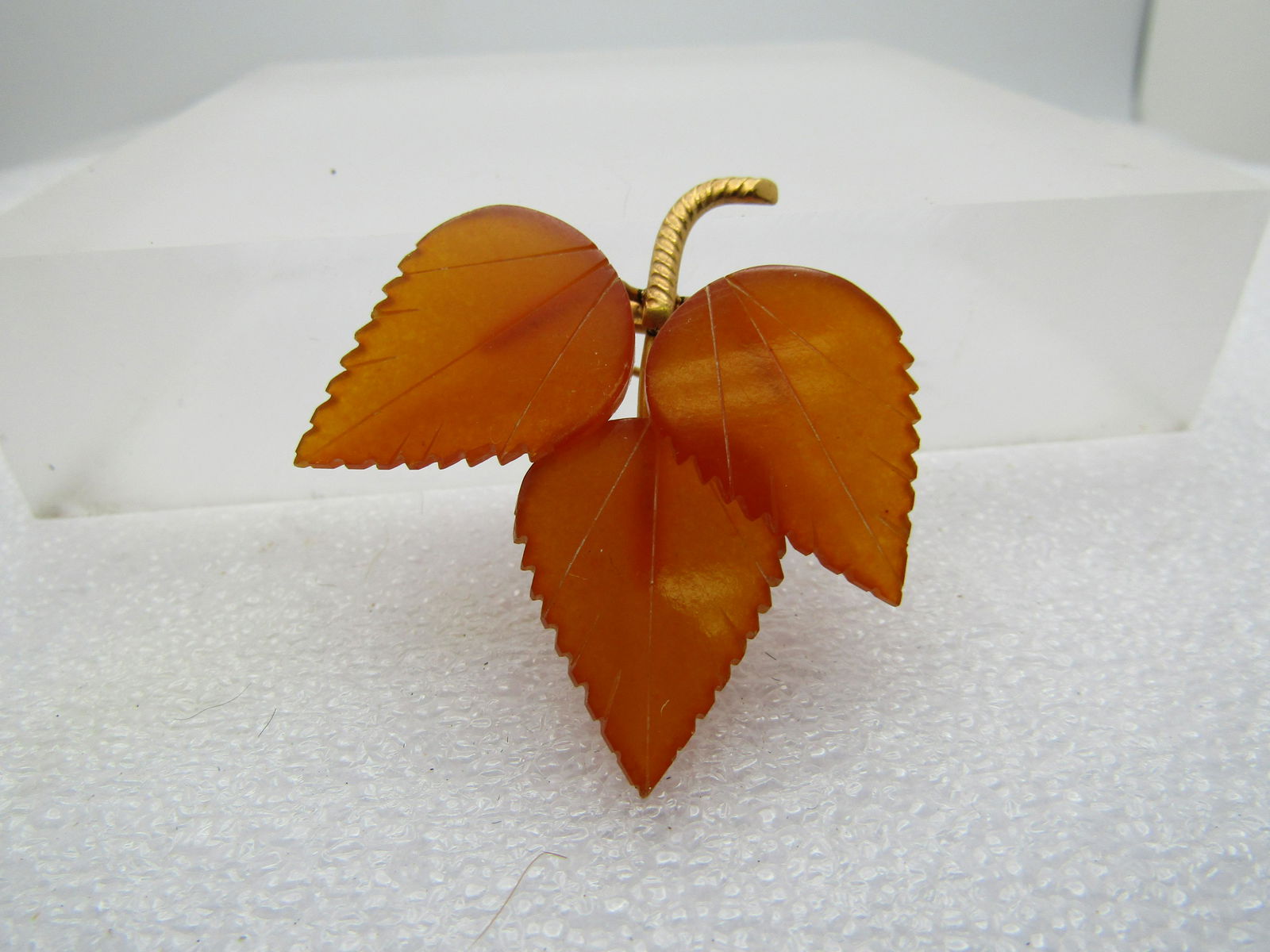 Vintage Carved Bakelite Triple Leaves Brooch, 1940's: Vintage Carved Triple Leaves Brooch, 1940's. Carved apple cider bakelite plastic leaves with jagged notched edges and a twisted gold tone stem. With the rub test, it does put off that odor you are loo