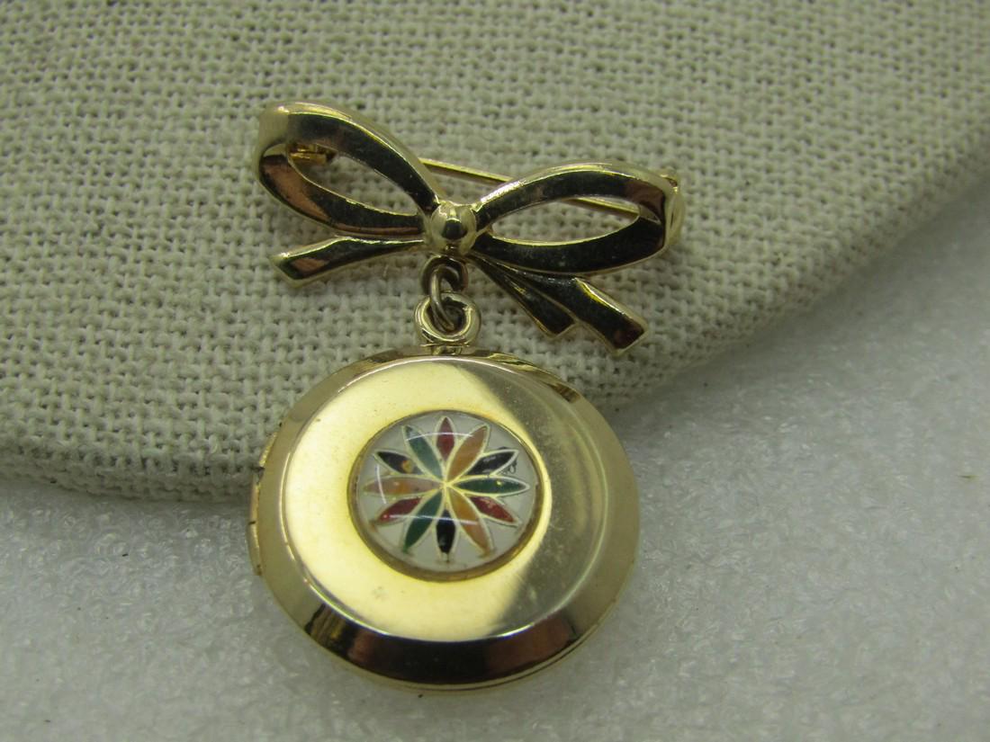Vintage Hex Sign Locket & Bow Brooch, 1960's-1970's: Vintage Hex Sign Locket & Bow Brooch, 1960's-1970's, 1.5" logn and 1-1/8" wide. A colorful hex symbol on the front of the hinged locket. (INV.W.82920.4 S2695 LD10/11/20) Reserve: $25.00 Shipping: Dome
