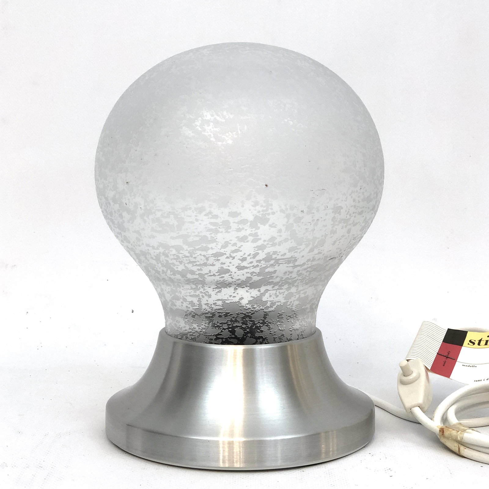 Mid-century Stilux Milano table lamp model Brioni. Labeled: Vintage never used in original condition with label and tag for this frosted glass and aluminum table lamp produced by Stilux Milano during the 60s. Material: frosted glass, aluminum Dimensions: H 24