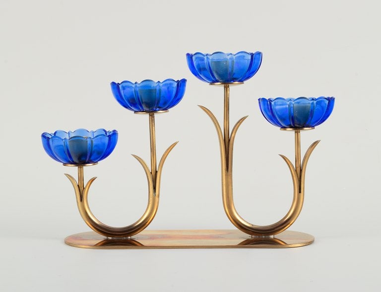 Gunnar Ander for Ystad Metall. Candlestick in brass and blue art glass shaped like flowers. 1950s.: Gunnar Ander for Ystad Metall. Candlestick in brass and blue art glass shaped like flowers. 1950s. Measures: 21 x 12.5 x 6.5 cm. In excellent condition with patina. Middle two glasses with insignifica