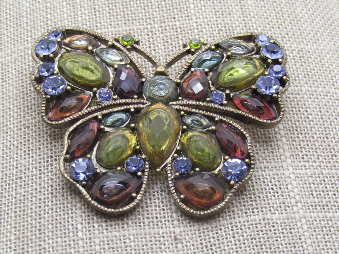 Vintage Rhinestone Butterfly Brooch, 1980's-1990's: Vintage Rhinestone Butterfly Brooch, 1980's-1990's. Acrylic rhinestones in blue, olive green and deep root beer colors set inside the wings and torso - lots of bling. The brooch is appx. 2" wide and 1