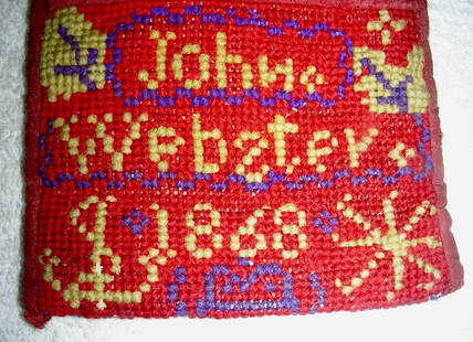 John Webster’s Needlework Wallet 1868: John Webster’s stitched needlework wallet dated 1868. (Note the backward “s” in Webster!) Deep red background with white and black decorations. John’s name and the date are sti