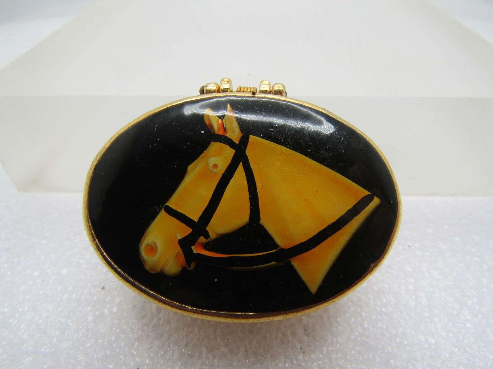 Vintage Horse Pill Box, Gold Tone, 1960's-1970's: Vintage Horse Pill Box, Gold Tone, 1960's-1970's. Gold tone with a weave look on the edges and a black background with a horse head with orange/yellow fur and a black halter. Great for the equestrian