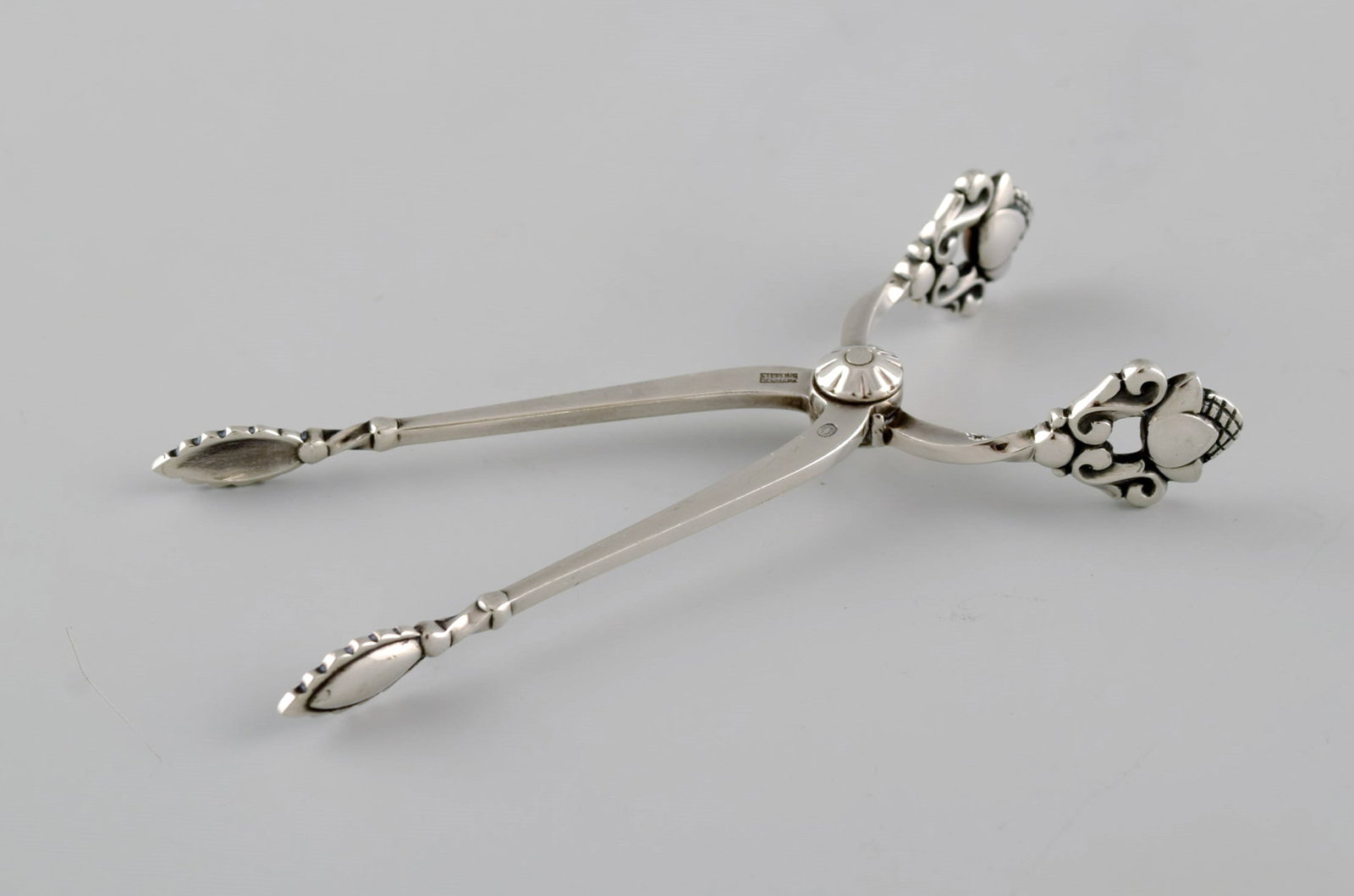 Georg Jensen Acorn sugar tong in sterling silver.: Title: Georg Jensen Acorn sugar tong in sterling silver. Description: Georg Jensen Acorn sugar tong in sterling silver. Measures: 9 x 5 cm. Stamped. In excellent condition. Our skilled Georg Jensen si