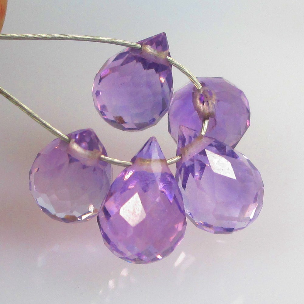 4.09 Ctw Natural 5 Drilled Purple Amethyst Pear Drop Beads: No Reserve! Title: 4.09 Ctw Natural 5 Drilled Purple Amethyst Pear Drop Beads Stone Clarity: Transparent Gemstone:Natural Amethyst Beads Carat Weights: 4.09 Size/Dimensions: 6.9x3.5 - 7.4x3.6 mm / 5 P