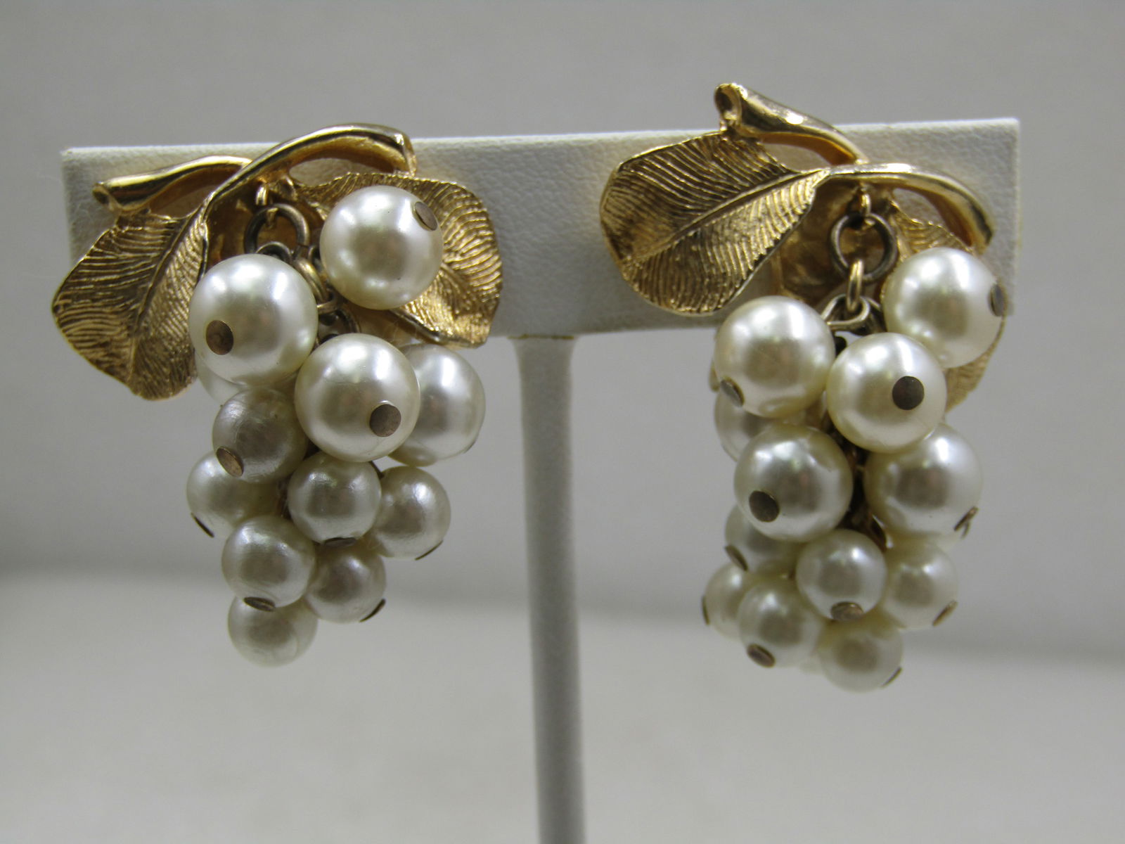 Vintage Faux Pearl Drop Cluster Earrings 1950s-1960s: Vintage faux pearl drop cluster earrings, clip. Appx.1. 5" long and 1" wide. Like a grape luster of pearls dangling from your ears. Gold tone textured leaves on top. Not signed or marked. 1950's-1960'