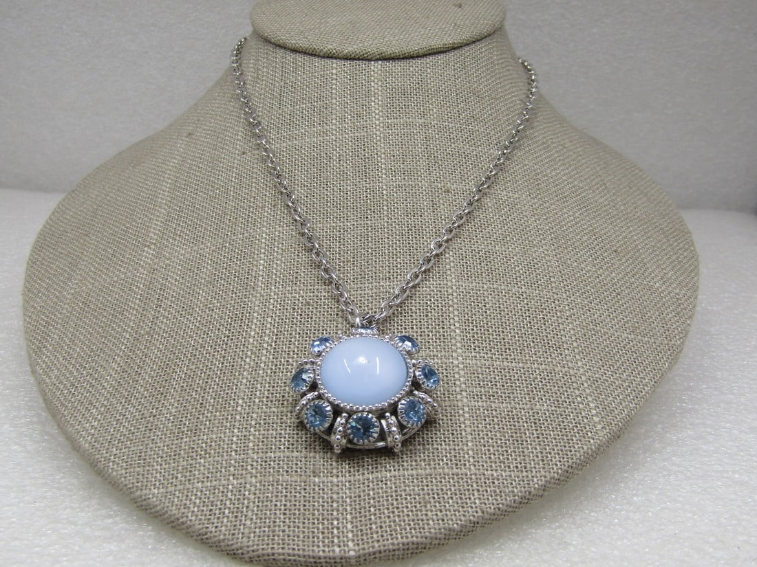 Vintage Avon Blue Moon Magic Rhinestone Necklace, 23": Vintage Avon Blue Moon Magic Rhinestone Necklace, 23" long silver tone chain. 1.25" long pendant that is appx. 1.25" wide. Center faux blue moonstone with baby blue rhinestones around the outer rim wi