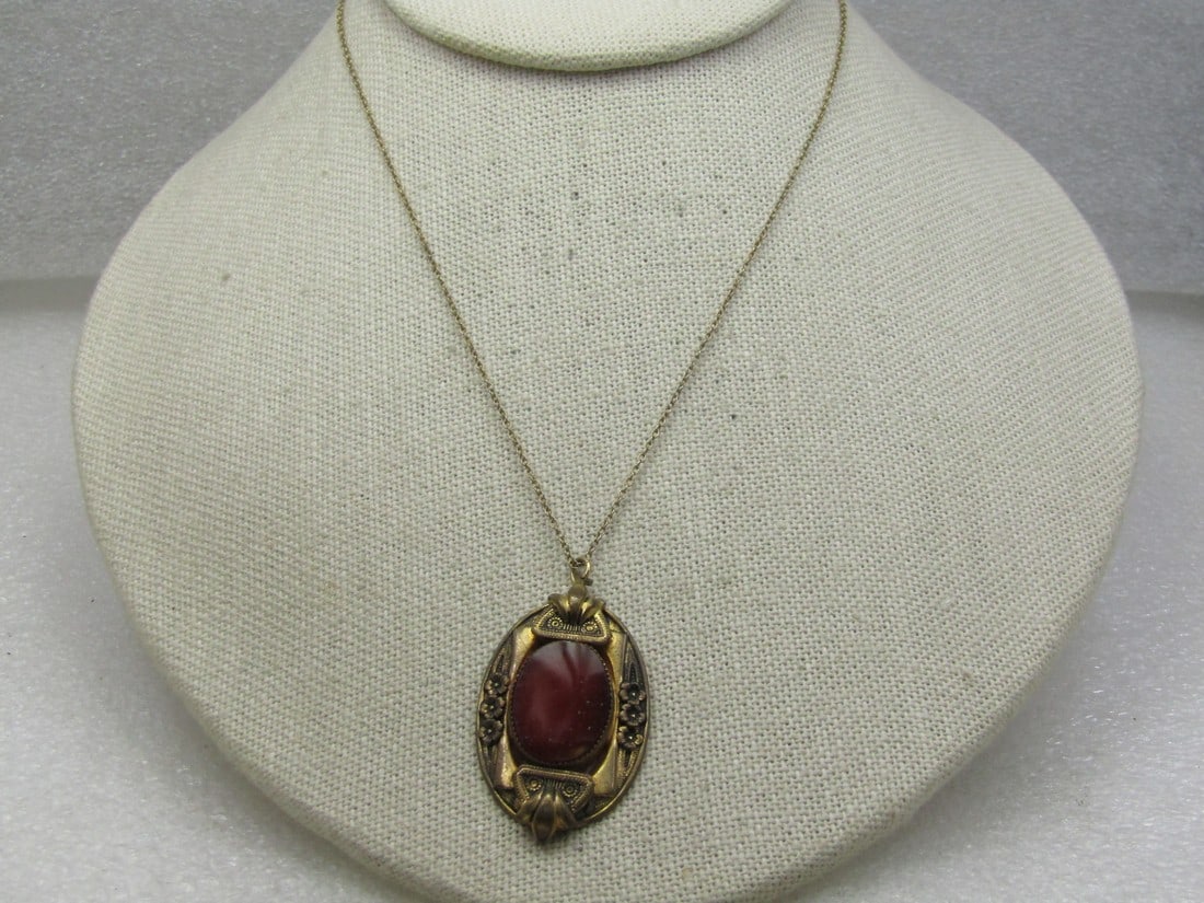Vintage Carnelian Necklace, Edwardian, 15": Vintage Carnelian Necklace, Edwardian, 15". Brassy gold tone pendant with floral accents and raised top and bottom above and below the stone with a jagged bezel-setting. The pendant is appx. 2.25" tal