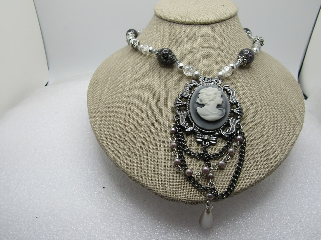 Beaded Cameo Draping Necklace, 1990's, Signed, 28": Beaded Cameo Draping Necklace, 1990's, Black/White/Clear, Signed, 28". It has clear and black crackle beads that are acrylic and faux pearls in a silver and white hue. The larger bads of decratie end 