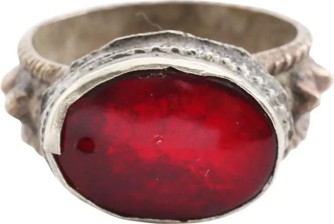 EASTERN EUROPEAN GYPSY RING, SIZE 9: 19th century. Size 9. White metal band, 7.9mm width, with roped edges flanking a band of high pyramidal spikes. Large oval bezel with cabled bottom and medial and raised central oval red "stone". Show