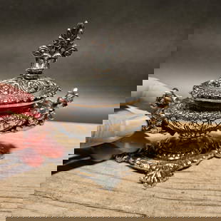 Ornate Nickel Plated Brass Inkwell Desk Stand: 4 1/2" Wide This aged, nickel-plated brass inkwell captures the essence of a bygone era, carefully crafted as a reproduction with elaborate ornamental designs on each side. It boasts a hinged lid that