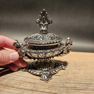 Ornate Nickel Plated Brass Inkwell Desk Stand: 4 1/2" Wide This aged, nickel-plated brass inkwell captures the essence of a bygone era, carefully crafted as a reproduction with elaborate ornamental designs on each side. It boasts a hinged lid