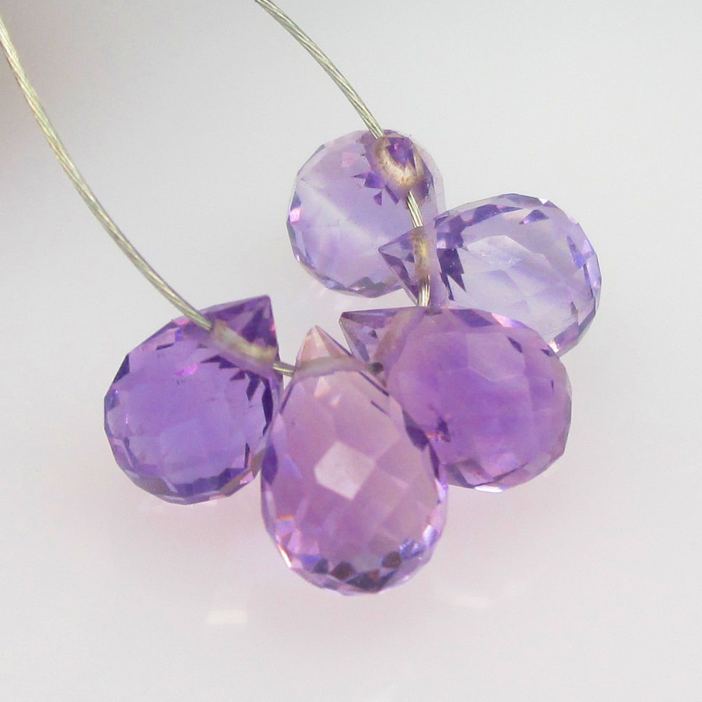 4.44 Ctw Natural 5 Drilled Purple Amethyst Pear Drop Beads: No Reserve! Title: 4.44 Ctw Natural 5 Drilled Purple Amethyst Pear Drop Beads Stone Clarity: Transparent Gemstone:Natural Amethyst Beads Carat Weights: 4.44 Size/Dimensions: 7.0x4.4 - 7.6x4.5 mm / 5 P