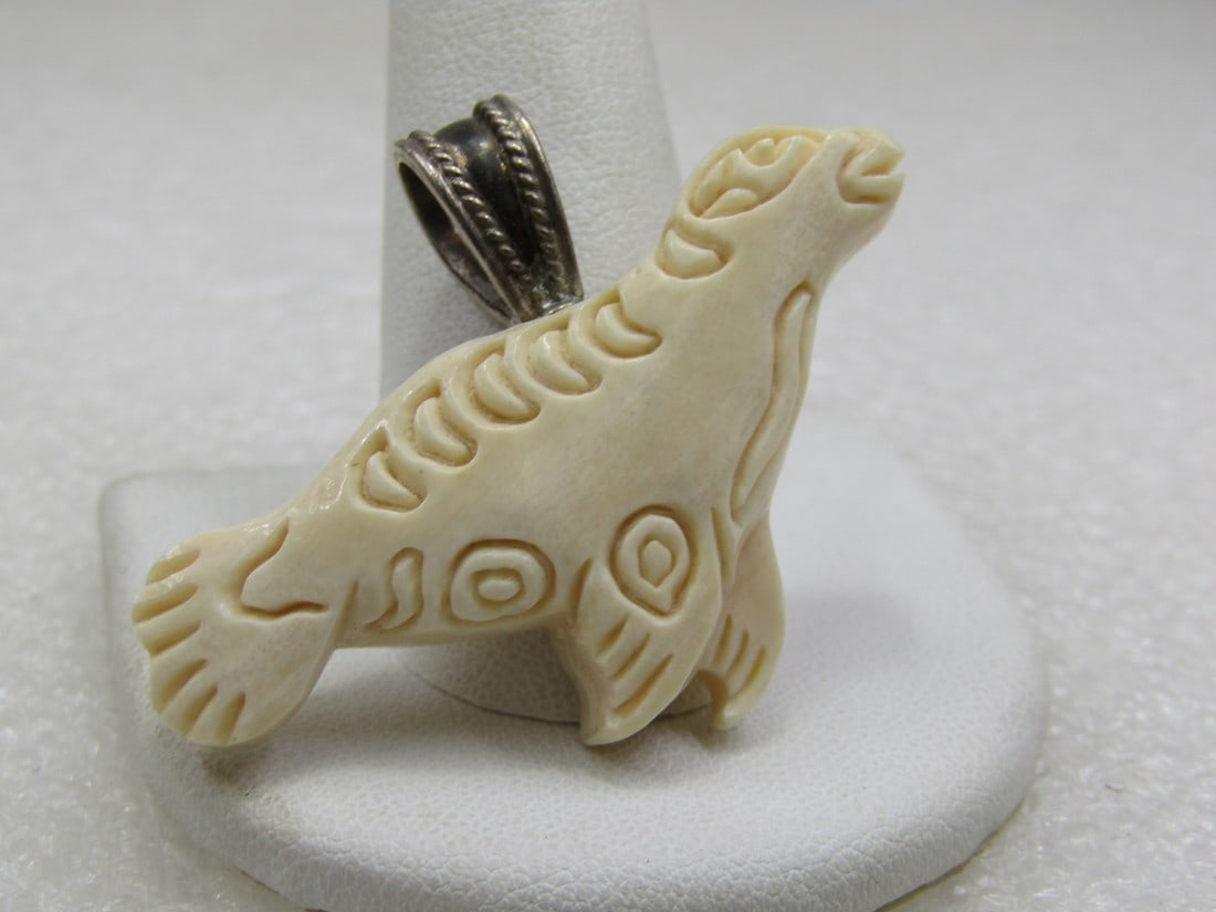Vintage Sterling & Bone Carved Seal Pendant, 1-7/8": Vintage Sterling & Bone Carved Seal Pendant, 1-7/8" wide and 1-3/8" tall. This has the looks of an Eskimo/Inuit design. It has a wide V bail on top, made of sterling silver that has an opening that is