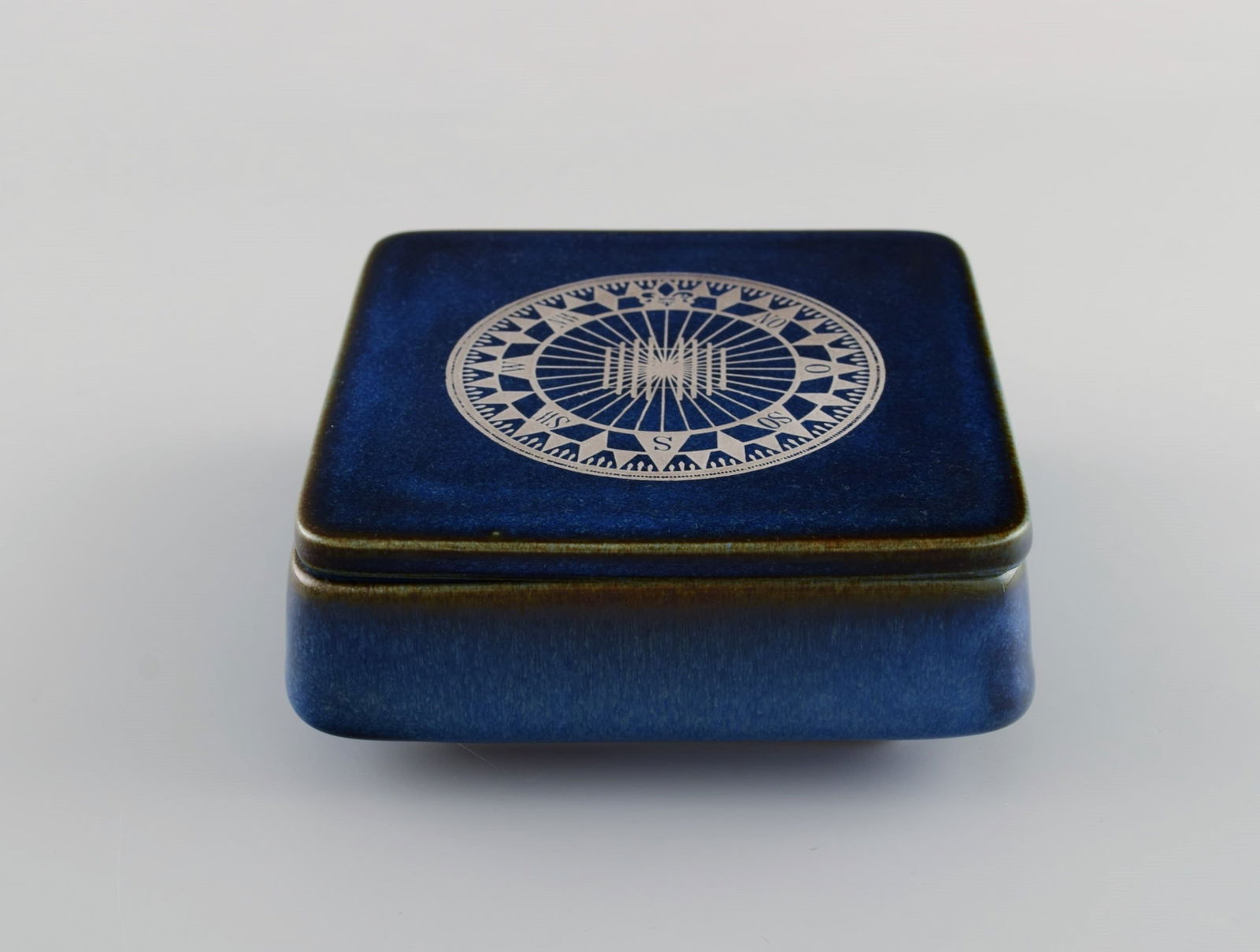 Sven Jonson (1919-1989) Gustavsberg. Lagun lidded box in glazed stoneware with silver inlay in the f: Sven Jonson (1919-1989) Gustavsberg. Lagun lidded box in glazed stoneware with silver inlay in the form of a compass. Beautiful glaze in shades of blue. 1970s. Measures: 14 x 14 x 5.5 cm. In excellent