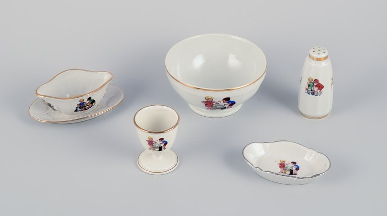French childrens porcelain dinnerware consisting of a bowl, egg cup, pepper shaker, miniature sauce: French childrens porcelain dinnerware consisting of a bowl, egg cup, pepper shaker, miniature sauce boat, and a small oval dish. Motifs of children at play. From the 1930s/1940s. In very good conditio
