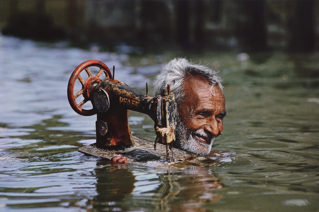 STEVE MCCURRY - A Tailor in a Monsoon, India, 1983: Artist: Steve McCurry Title: A Tailor in a Monsoon, Porbandar, India, 1983 Medium: Photo Litho, 2012, Italy Dimensions: 13.95x9.3" Description: Heat Wax Mounted on 14x18" Conservation Board Artist Bio