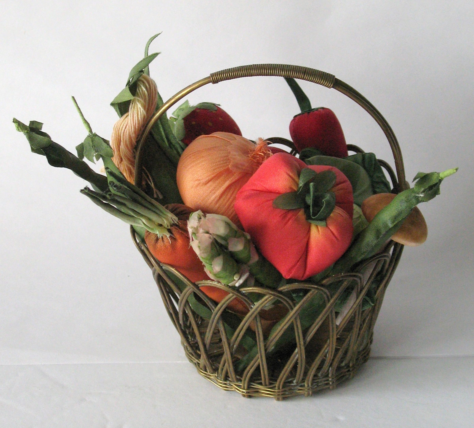 Vintage miniature veggies in a small brass basket.: Title: Vintage miniature veggies in a small brass basket. Date/Period: 1950's Dimension: basket is 5 1/2” high Additional Information: Group od vintage miniature fabric veggies in a small brass 