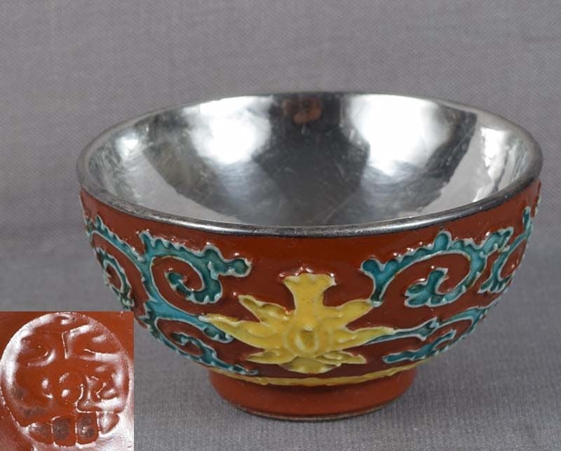 19c Japanese porcelain sake cup by EIRAKU: 19th century/Meiji period Japanese porcelain sake cup with silver liner on the inside and decoration of flowering lotus flowers among scrolling vines above stylized clouds. The cup is decorated in fa-