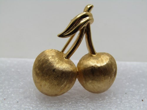 Vintage Cherries Brooch, Crown Trifari, 1960's-1970's: Vintage Cherries Brooch, Crown Trifari, 1960's-1970's. Gold tone and appx. 1" by 1", textured and smooth finish. Two cherries on a stem. Classic design. Very good condition and signed on the back. (W9
